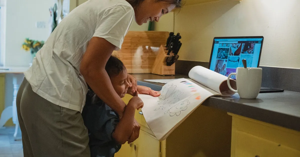 Mother and child at a kitchen table applying for child tax payday loans on a laptop