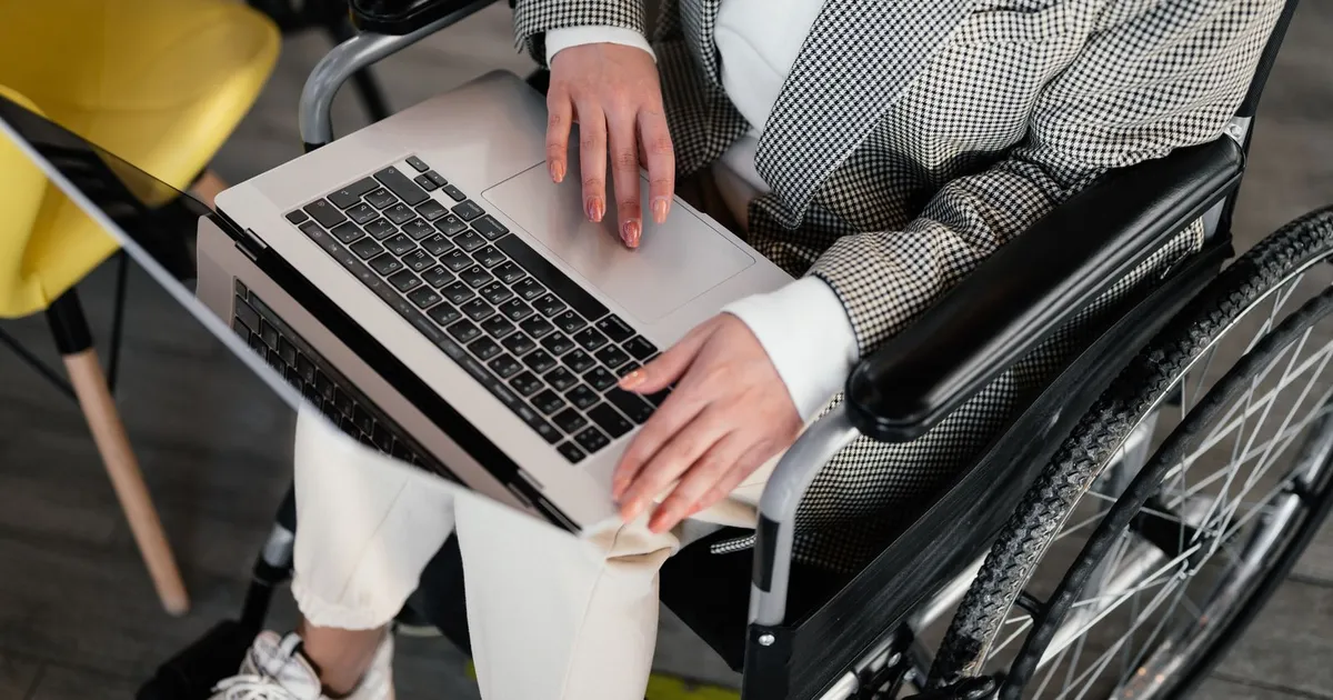 Man in a wheelchair applying for payday loans disability income supports on a laptop at his kitchen table